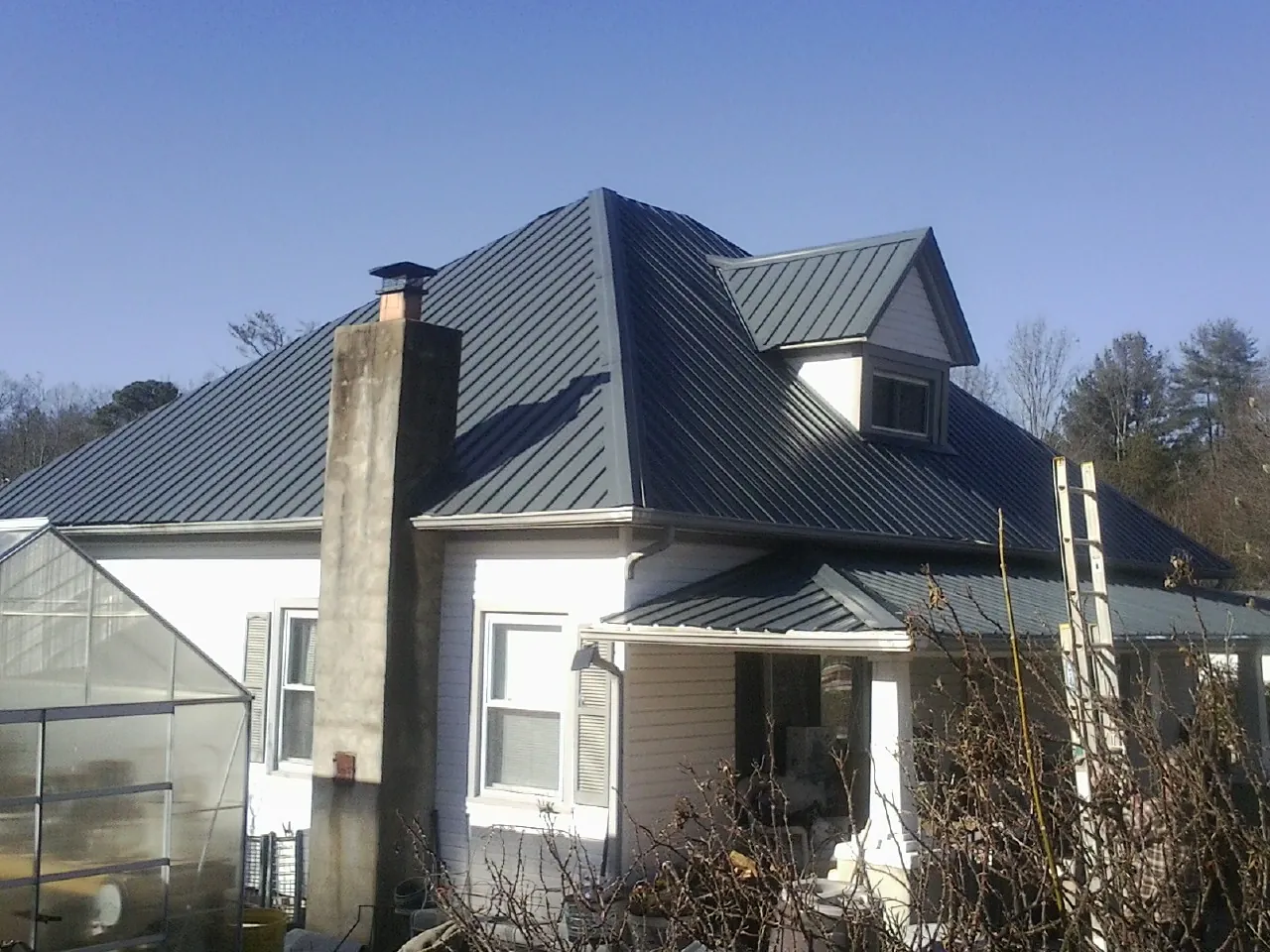 Dark blue standing seam metal roof on a white farmhouse with dormer — Slate & Tile Roof Repair by Roofing Brothers in Tatamy