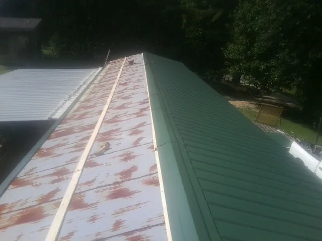 Old rusted panels beside newly installed green metal roofing — Wind Damage Roof Repair by Roofing Brothers in Tatamy