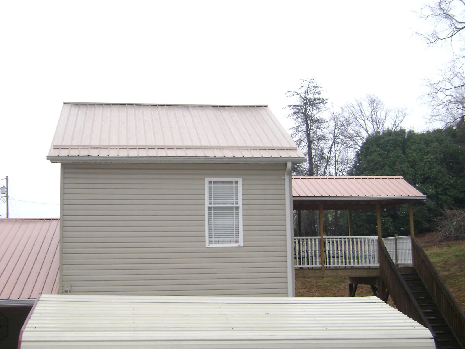 Tan metal roofs on a two story addition and attached porch, from a Roof Replacement job in Tatamy