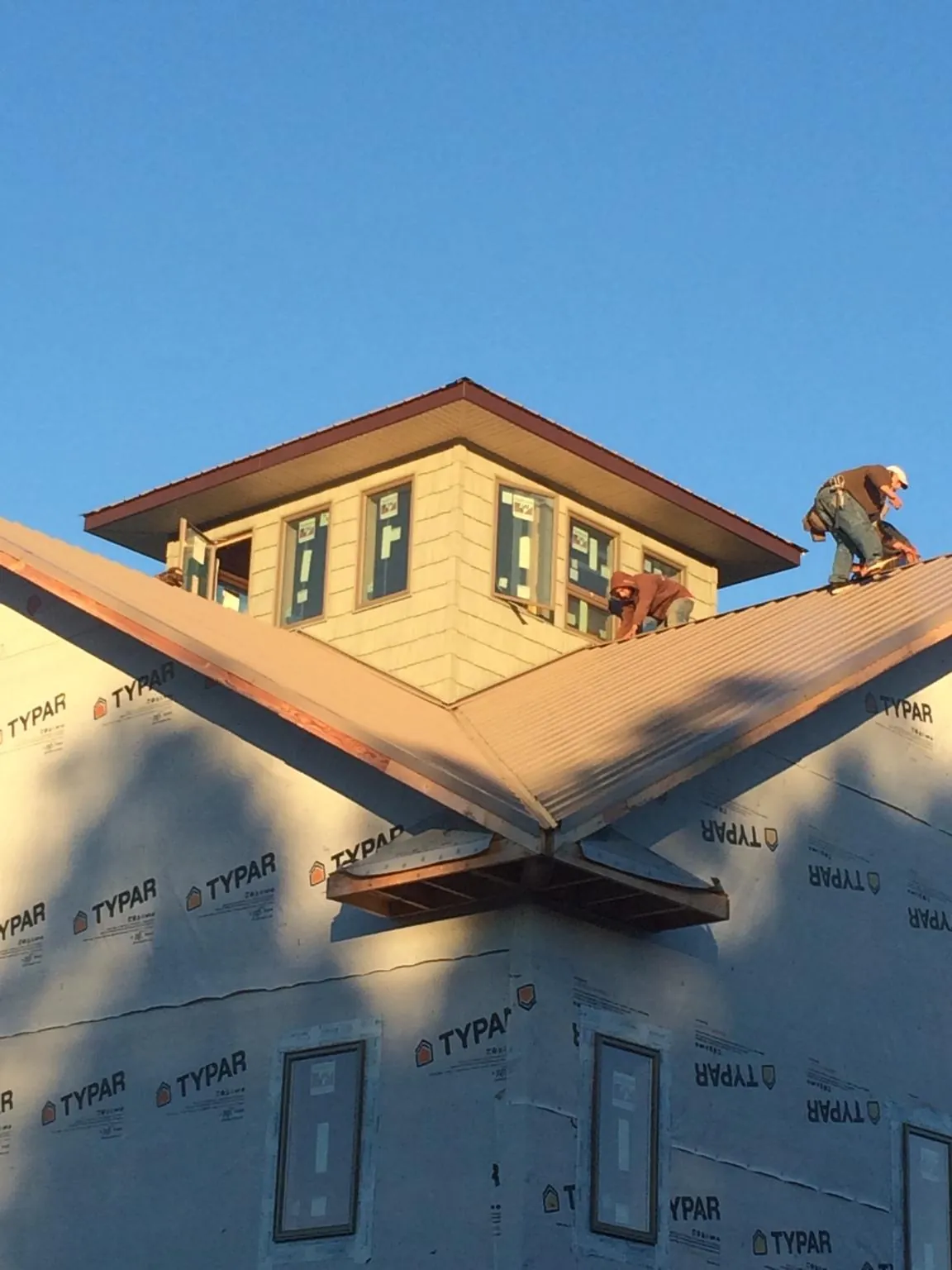 Roofers working around a rooftop cupola on a new metal roof at sunset — Roof Waterproofing in Tatamy by Roofing Brothers